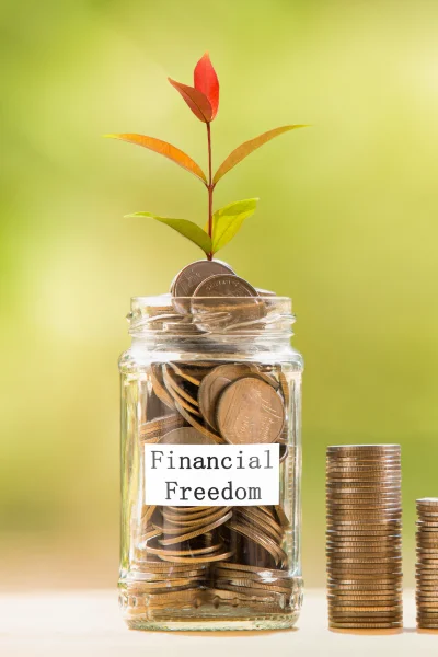 A glass jar filled with coins, with a small flower sprouting from the top. The jar is labeled with the words 'financial freedom.'